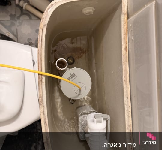 מבט אל תוך ניאגרה גלויה פתוחה בעת תיקון והחלפת מצוף ומנגנון הדחה